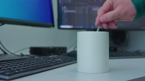A man's hand continues to stir a liquid with a spoon in a white mug Stock Footage 273307952