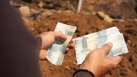 A man's hand counting two thousand rupiah notes outdoors Video stock 253774748