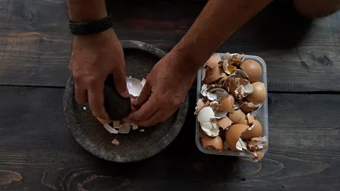 A man's hand is crushing an egg shell using a mortar. Stock Footage 254381569