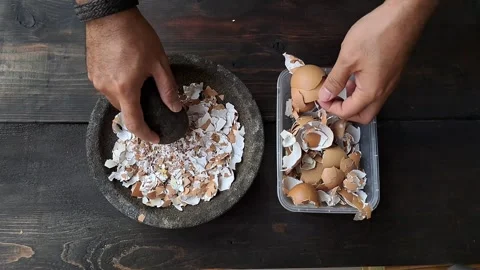 A man's hand is crushing an egg shell using a mortar. Stock Footage 254381570