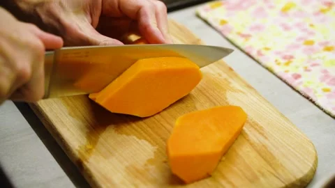Man's hand cuts an orange pumpkin on cutting board into slices 库存影片 232892730