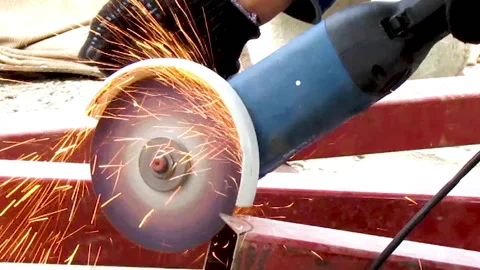 A man's hand cuts off a piece of iron pipe using an angle grinder Stock Footage 159484160