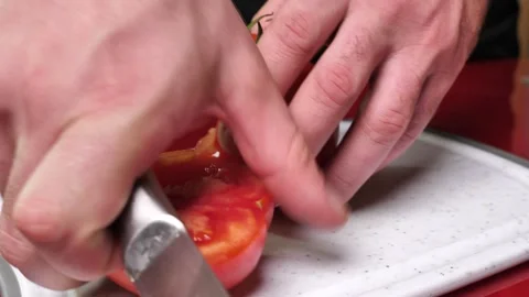 A man's hand cuts a red tomato into pieces. preparation of vegetables for s.. Stock Footage 254610257