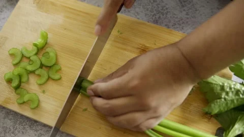 Man's hand cutting celery on a bamboo cutting table Stock Footage 272182003