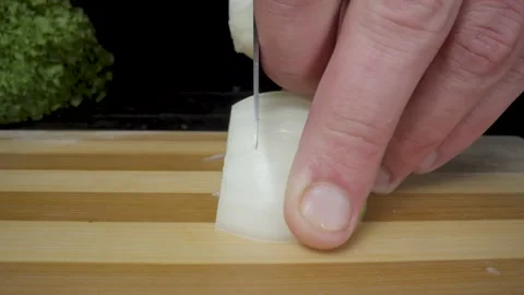 A mans hand cutting half an onion with a knife. Chopping an bulb on a wooden Stock Footage 203022851