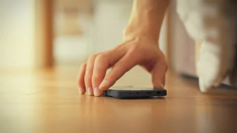 A mans hand dangles over the bed edge searching for his phone to silence the Stock Footage 331452785