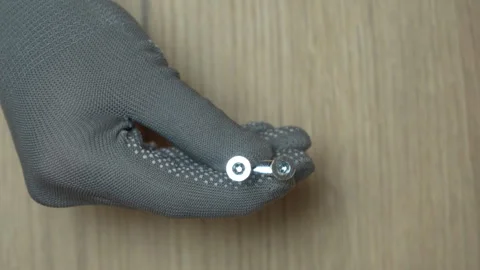 A man's hand demonstrates two confirmatory dowels to the camera Stock Footage 303473172