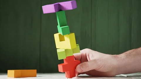 Man's hand is destroying a tower of colored wooden blocks, slow motion. Stock Footage 89507059