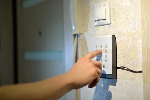 Man's hand dials the code from the security system at home on a keypad with Stock Photos