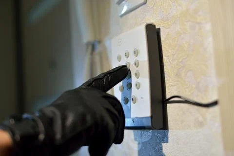Man's hand dials the code from the security system at home on a keypad with Stock Photos