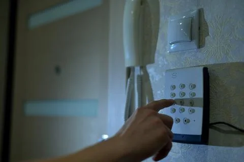 Man's hand dials the code from the security system at home on a keypad with Stock Photos