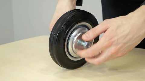 A man's hand disassembles a rubber wheel with a metal disc for a trolley Stock Footage 172107244