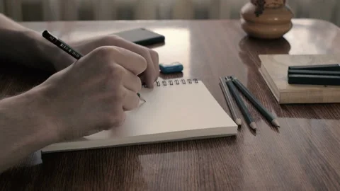 Mans hand drawing on notebook page with black pencils Stockbeeldmateriaal 102793079