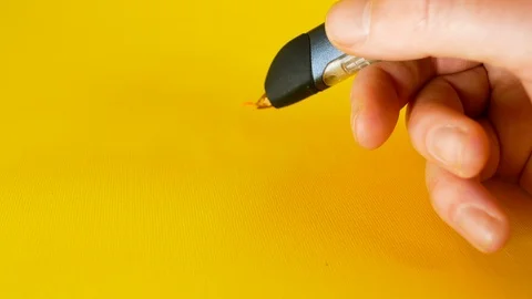 A man's hand draws with a 3d printer pen on a yellow background, footage ideal Video stock 103372872