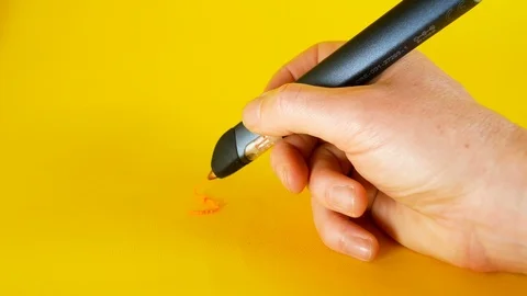 A man's hand draws with a 3d printer pen on a yellow background, footage ideal Stockbeeldmateriaal 103375345