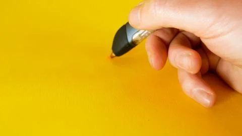 A man's hand draws with a 3d printer pen on a yellow background, footage ideal Foto stock