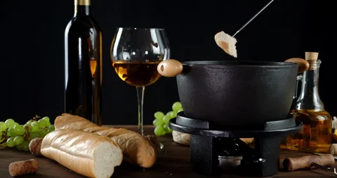 The man's hand dunks a piece of bread in fondue with wine. Stock Footage 129141041