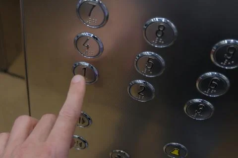 The man's hand in the elevator presses the first floor button. Metal surface, Stock Photos