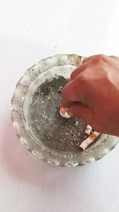 A man's hand extinguishes a cigarette butt in an ashtray Stock Footage 324851482