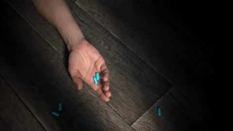 Man's hand falls to the floor, dropping pills. Stock Footage 260568332