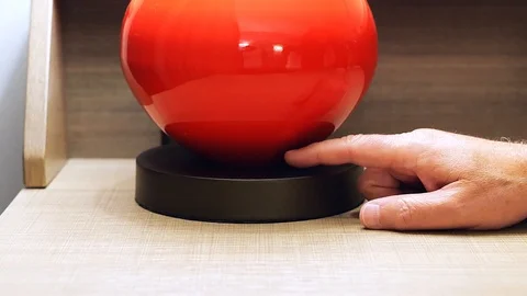 Mans hand finger pushes switch of red desk lamp to turn off the light. Stock Footage 126127891