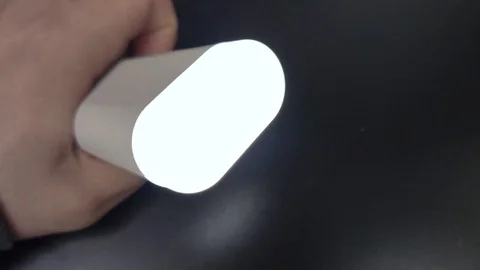 In the man’s hand, a flashlight on a power bank turns on. The concept of univers Stock Footage 125102162