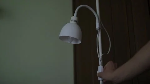 Man's hand flicking the switch on a white floor lamp. Stock Footage 322098522