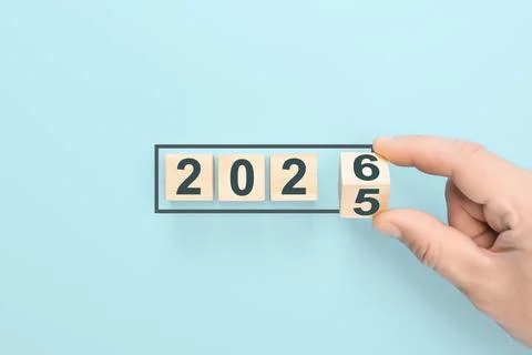 Man's hand flips final cube to form 2026. Represents transition from 2025, st Stock Photos