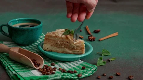 Man's hand with fork breaks off piece of Cake Napoleon on a Green Background Stock-Footage 235896057