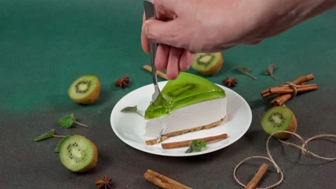 Man's Hand with fork breaks off piece of Cheesecake with Kiwi Stock Footage 236412718