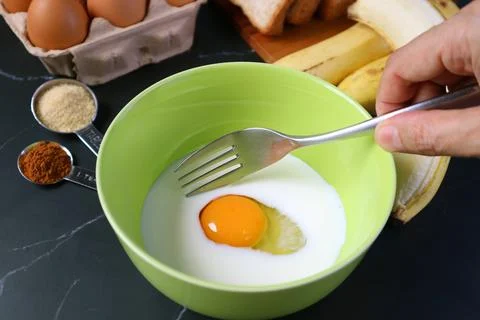 Man's Hand with Fork Going to Mix Egg and Milk in the Mixing Bowl Foto stock