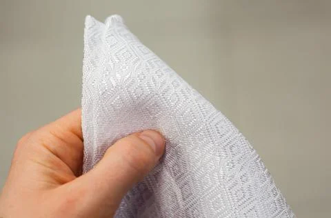 A man's hand in the frame holds a triangular white napkin on a blurred backgr 写真素材