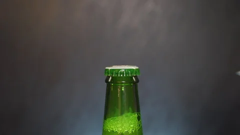 Man's hand in the frame opens a green beer bottle Stock Footage 102918334