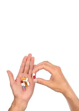 A man's hand is full of a large pile of different pills. Vertical photo. Stock Photos