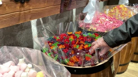 A man's hand in a glove in a store takes a marmalade from a barrel Stock Footage 162575752