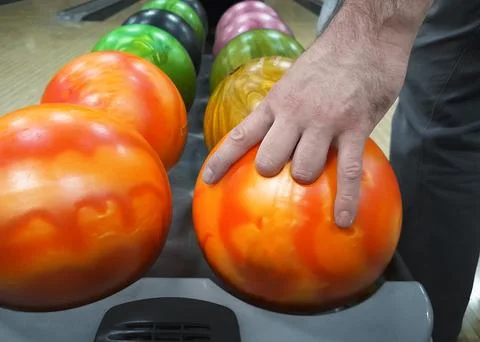A man's hand grabs a bowling ball and removes it from the rack. Bowling gam.. Stock Photos