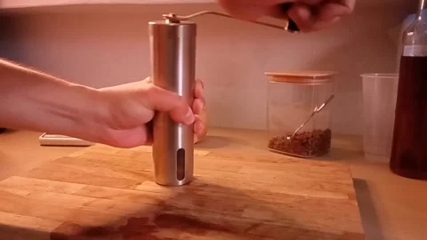 A man's hand grinds coffee beans with manual coffee grinder Stock Footage 340356942