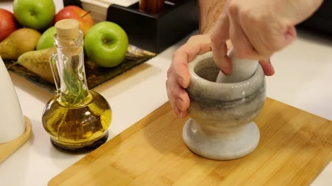 A man's hand grinds pepper in mortar and pestle crushing spices for seasoning Stock Footage 270442916