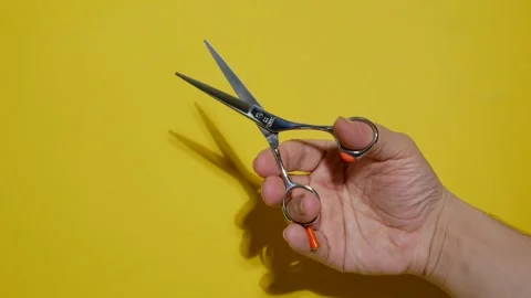 A man's hand with hairdressing scissors on a bright yellow paper background. Stock Footage 164376071