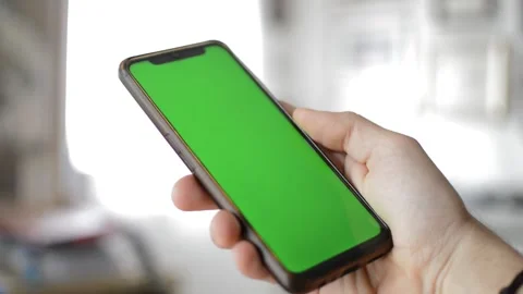 Man's hand hold iphone device by apple with green screen display. Stock Footage 237431157