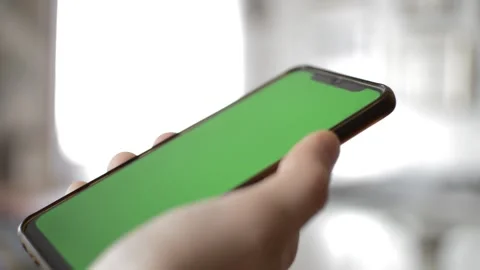 Man's hand hold iphone device by apple with green screen display. Stock Footage 237431215
