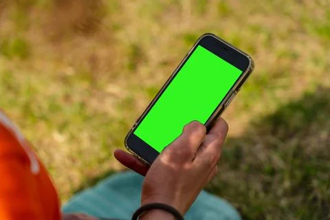 Man's hand holding and using mobile smart phone on nature Stock Photos