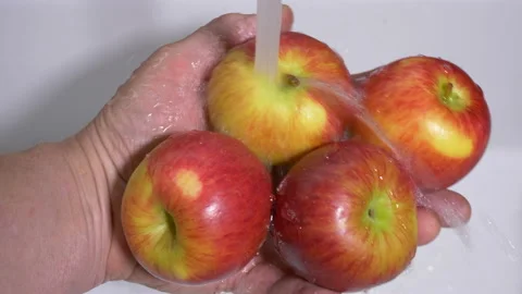 Man's hand holding apples under a running sink tap. Video stock 159798356