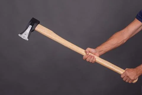 A man's hand holding an axe for chopping wood. Stock Photos