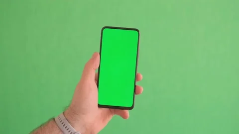 Man's hand holding a black smartphone with green screen and touching or press Stock Footage 242503012