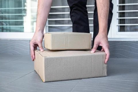 Man's hand holding boxes at the front door to receive package, shipping deliv Stock Photos