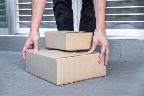Man's hand holding boxes at the front door to receive package, shipping deliv Stock Photos