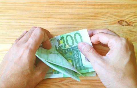 Man's Hand Holding a Bundle of 100 EURO Banknotes on Wooden Backdrop Stock Photos