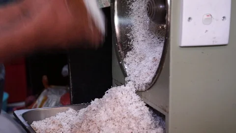 The man's hand is holding coconuts to grate on coconut grate. Stock Footage 104950317