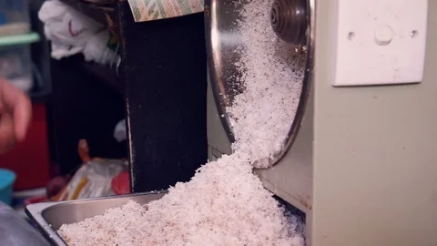 The man's hand is holding coconuts to grate on coconut grate. Stock Footage 104991747